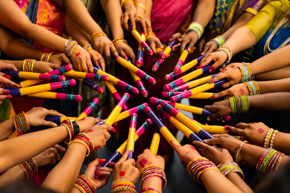People holding colourful dandiya sticks at a Navratri celebration